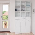 Modern white kitchen display cabinet with glass doors next to patio door with golden retriever looking inside